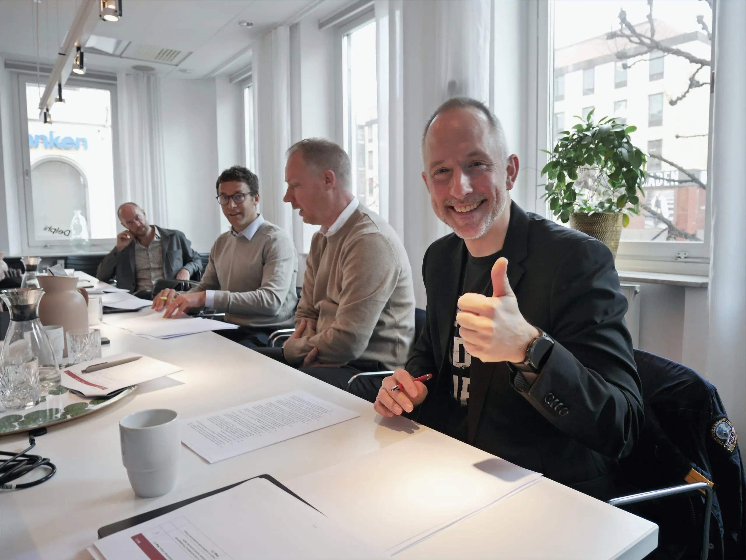 Fyra personer vid signeringsbordet, en av dem gör tummen upp